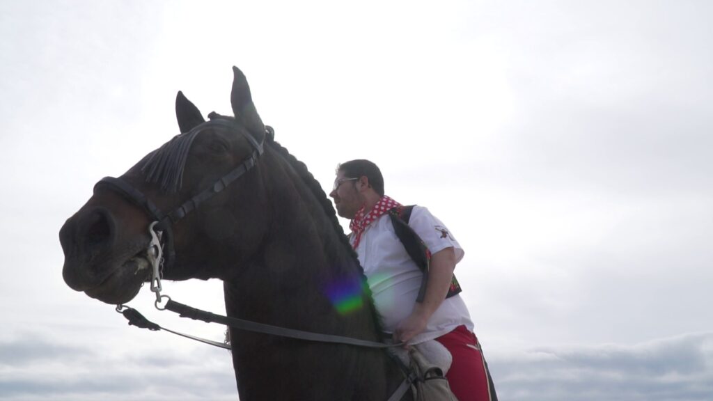 Festero con pañuelo rojo y blanco montando un caballo negro.
