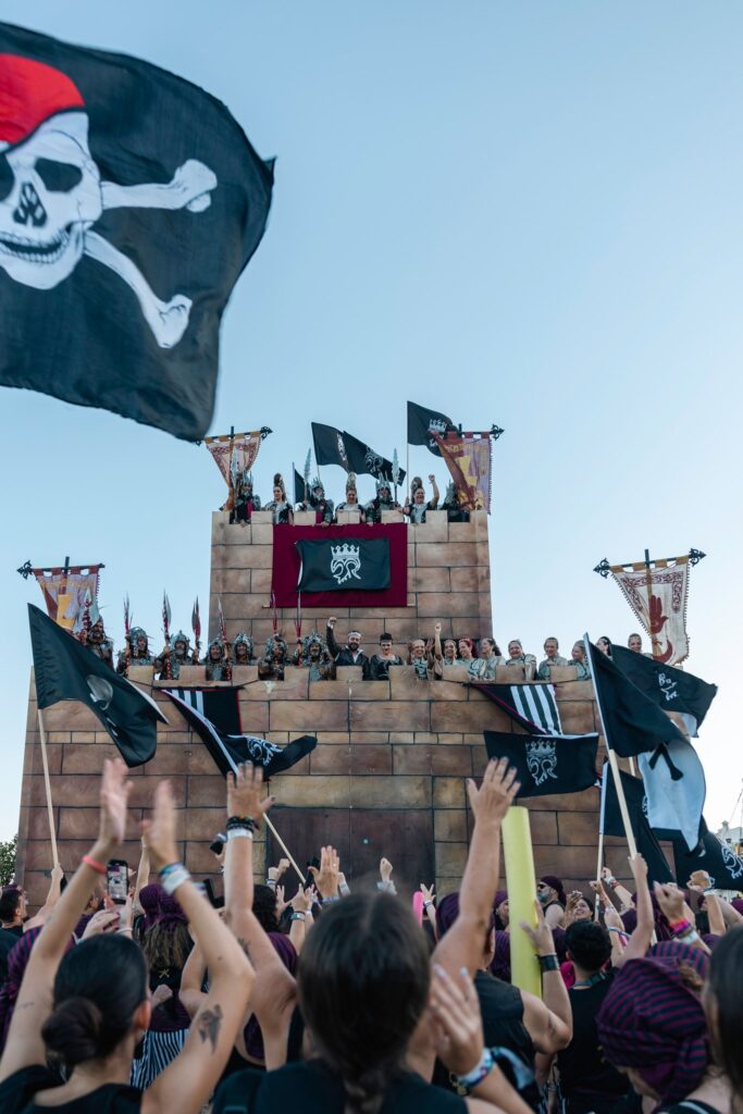 Banderas piratas y festeros celebrando ante el castillo de Villajoyosa.