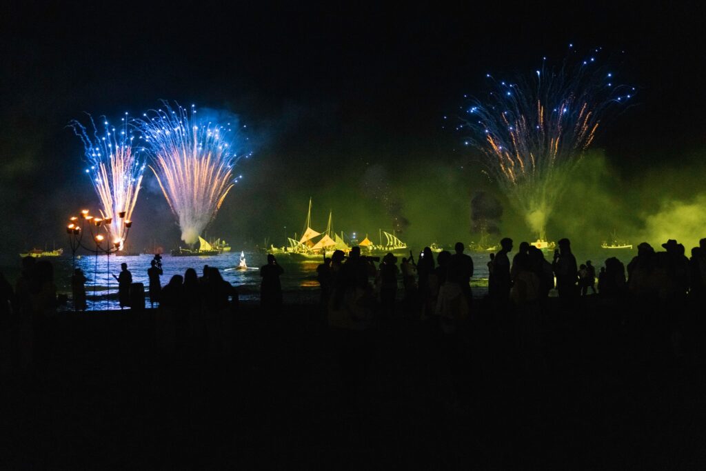 Fuegos artificiales y embarcaciones frente a la playa de Villajoyosa al anochecer.