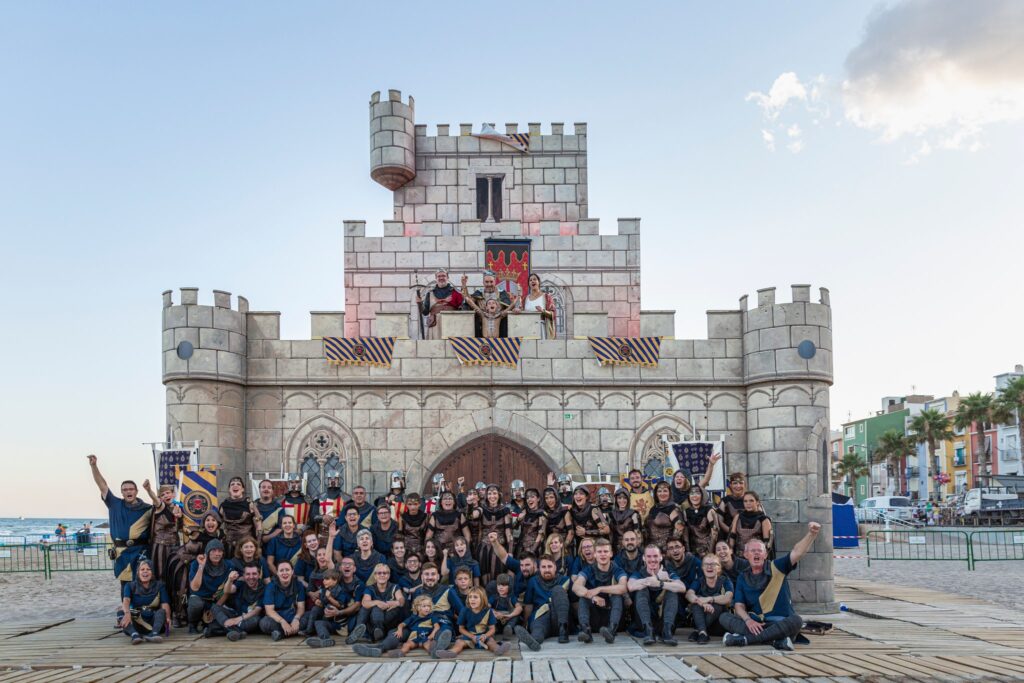 Grupo de festeros posando ante el castillo junto al paseo marítimo de Villajoyosa.