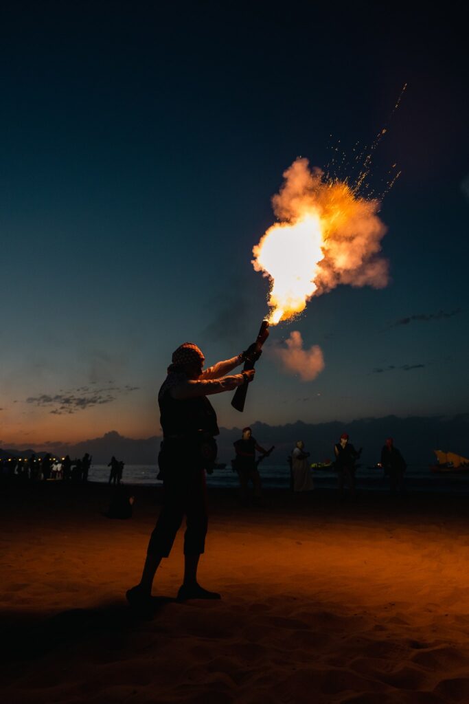 Festero disparando un arcabuz ceremonial en la playa de Villajoyosa al atardecer.