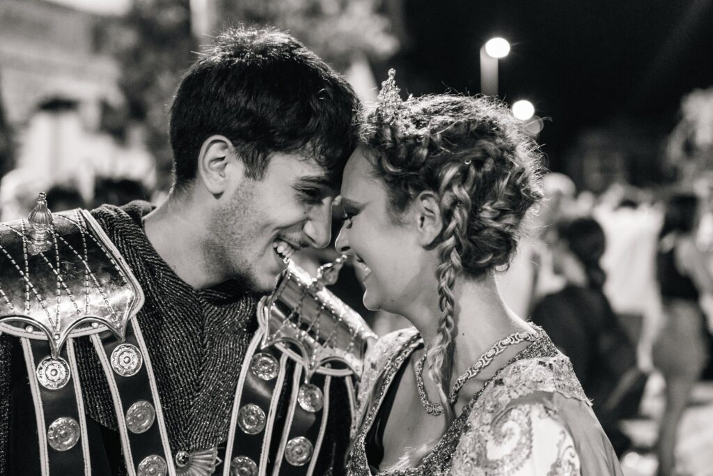 Pareja con trajes de Moros y Cristianos sonriendo con las frentes juntas, en blanco y negro.