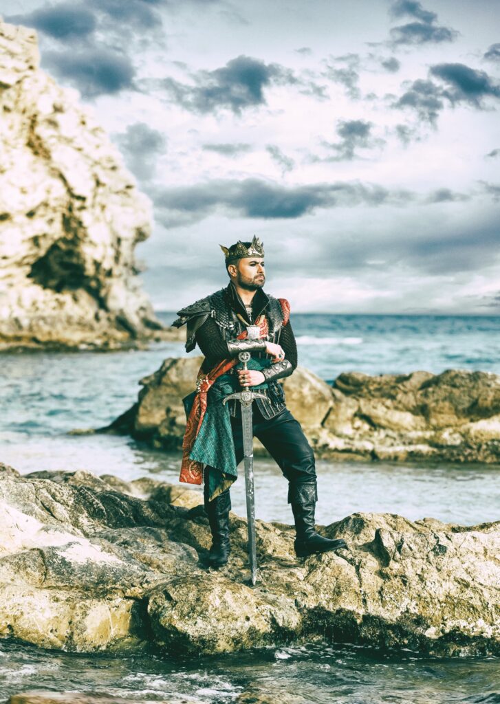 Retrato oficial de Mati con corona, armadura y espada junto al mar para el libro de fiestas de Villajoyosa.