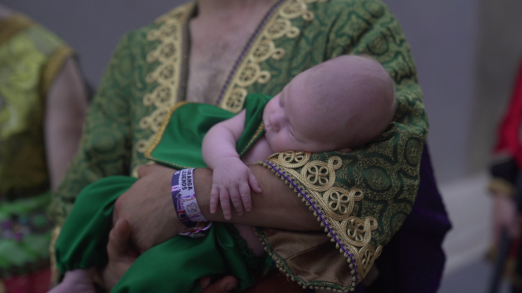 Un bebé con indumentaria festera en brazos de su familia durante los Moros y Cristianos